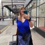 Picture of me travelling, holding a suitcase and a phone at victoria station London