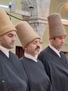 3 priests concentrating before the whirling dervish in Istanbul