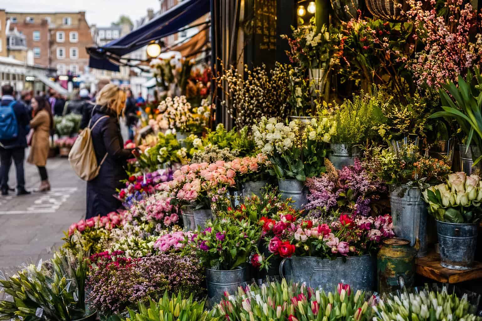 Flower market with roses and a woman paying a bouquet of flowers